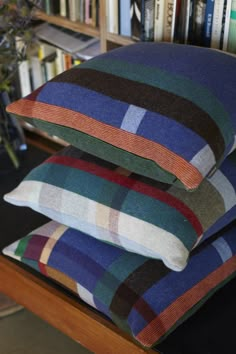 three pillows stacked on top of each other in front of a book shelf filled with books