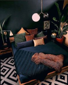 a bed with pillows and blankets on top of it in a room filled with potted plants