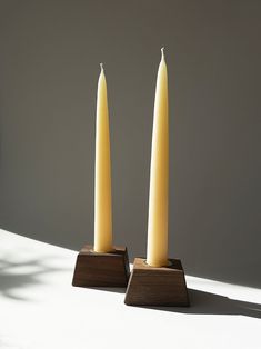 two candles sitting on top of each other in front of a white wall and floor