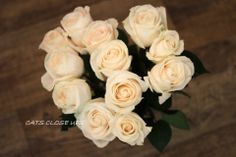 a bouquet of white roses sitting on top of a wooden table