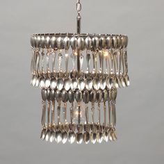 a chandelier with spoons hanging from it's sides and the lights turned on