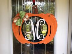 an orange pumpkin shaped wreath with the letter m on it's front door hanger