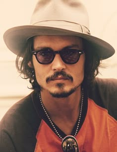 a man wearing sunglasses and a hat with beads around his neck is looking at the camera