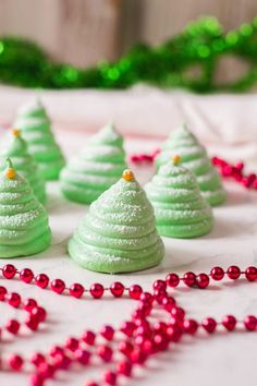 green christmas tree meringue cookies on a white table with red and green beads