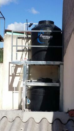 a black tank sitting on top of a metal rack next to a building with a blue sky in the background