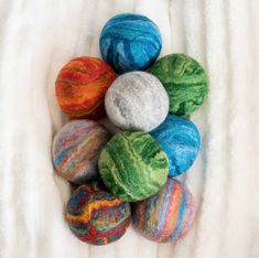 several balls of yarn sitting on top of a white blanket with one ball in the middle