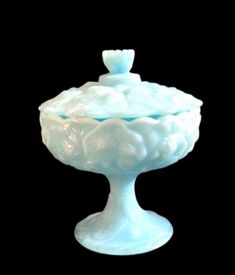 a white glass bowl sitting on top of a black surface with clouds in the center