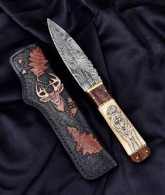 two knives are laying next to each other on a black cloth covered surface with an intricate design