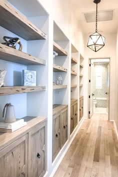 an empty room with wooden shelves and white walls, along with a light fixture hanging from the ceiling