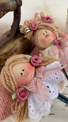 two little dolls are sitting next to an old sewing machine and some knitting needles in front of them