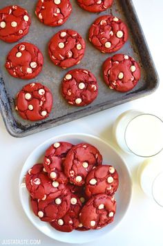 red velvet cookies with white chocolate chips on a baking sheet next to a glass of milk