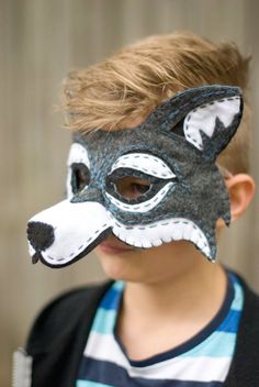 a young boy wearing a gray and white mask with a wolf's head on it