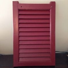 a red shuttered window sitting on top of a wooden floor