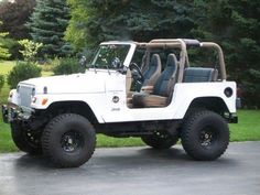 a white jeep is parked in front of some trees