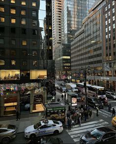 a busy city street filled with lots of traffic and tall buildings in the evening hours