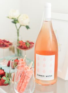 a bottle of water and some strawberries on a table with drinks in the background