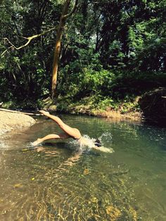 a woman is swimming in the river with her legs spread out and arms extended up