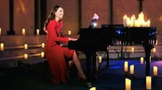 a woman sitting at a piano surrounded by candles