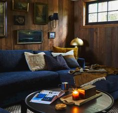 a living room with wood paneling, blue couch and coffee table in front of it