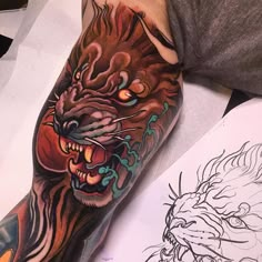 a man with a tiger tattoo on his arm next to a drawing and pencils