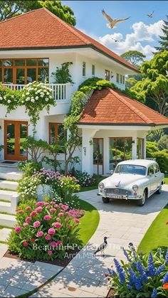 a white car parked in front of a house with flowers on the lawn and steps leading up to it