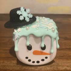 a snowman wearing a black hat and blue icing on it's head