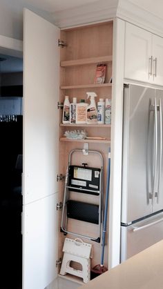 a kitchen with white cabinets and stainless steel refrigerator freezer combo in the corner, next to an open pantry door