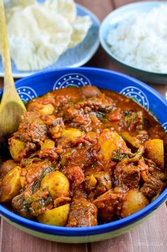 a blue bowl filled with stew next to rice