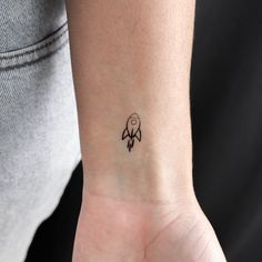 a small tattoo on the wrist of a woman's hand, with a rocket ship