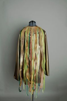 a mannequin is covered with ribbons and streamers in gold, green, and brown