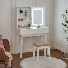 a white vanity table with a lighted mirror and stool