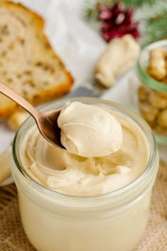 a spoon full of cream sitting on top of a table next to bread and nuts