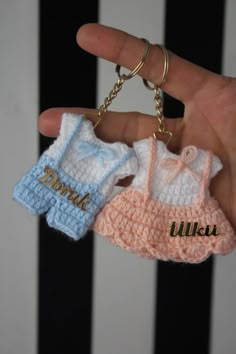 two small crocheted key chains are being held by a person's hand