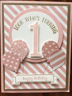 a pink birthday card with balloons and a number one on the front, says look who's turning 1