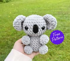 a small crocheted koala bear sitting on top of a grass covered field