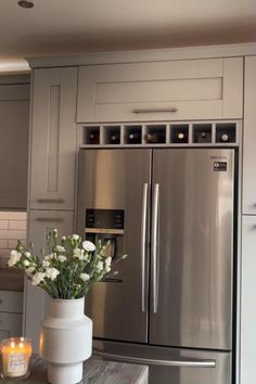 a vase filled with flowers sitting on top of a kitchen counter next to a refrigerator