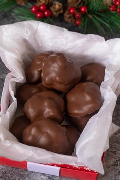 chocolate candies in a red box on a table with pine cones and evergreen branches