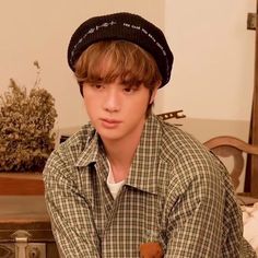 a young man wearing a hat sitting on top of a wooden table