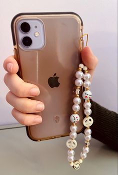 a person holding an iphone in their hand with pearls on the phone chain attached to it