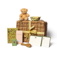 a teddy bear sitting on top of a wicker basket next to cards and other items