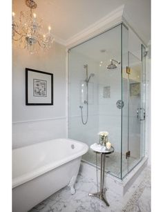 a white bath tub sitting under a chandelier next to a walk in shower