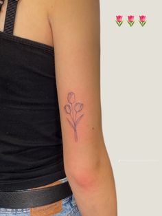 a woman's arm with a small flower tattoo on the back of her left arm