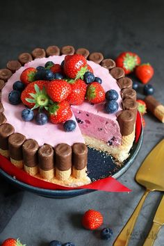 a cake with chocolate, strawberry and blueberries on top is sitting on a plate