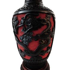 a red and black vase sitting on top of a wooden stand