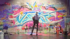 a man standing in front of a wall with graffiti on it's walls and looking up at the ceiling