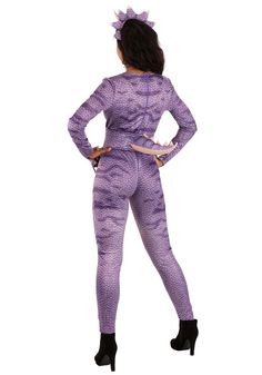 a woman in a purple bodysuit and black boots is standing with her hands on her hips