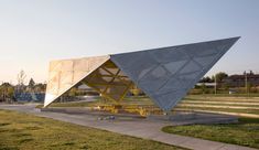 a large triangular structure sitting on top of a lush green field