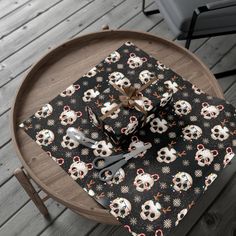 a table topped with a black and white present box covered in skulls next to a knife and fork