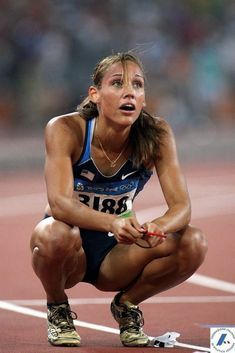 a woman kneeling down on top of a track