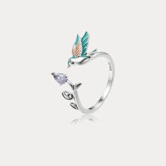 a silver ring with a bird on top and two leaves around the band, set against a white background